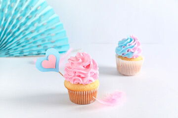 Delicious cupcakes with decorations on table against white background. Gender reveal party concept