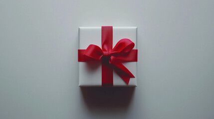 A gift box adorned with a red ribbon, set against a pure white background.