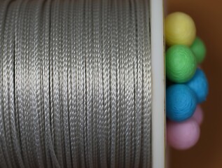 A close-up photograph of a kite string spool, with taut thread and colorful accents