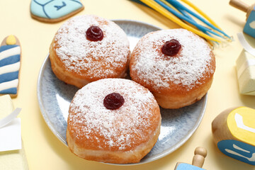 Plate with tasty donuts and decor for Hanukkah celebration on color background