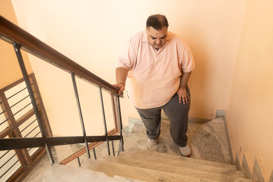 Overweight indian man have difficulty climbing stairs, Plus size guy have knee pain and fatigue. fitness healthcare, obesity. Lose weight,