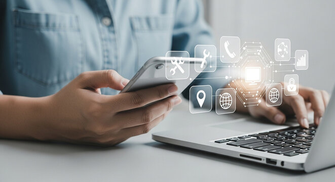 Person using laptop and holding smartphone with digital icons floating above the devices