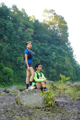 Asian Couple Resting on Trail Run in Rocky Forest Landscape