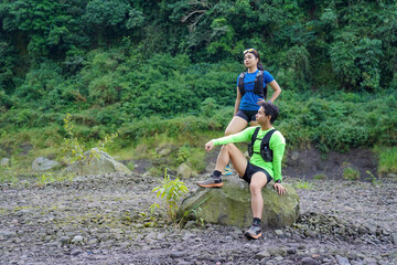 Asian Couple Resting on Trail Run in Rocky Forest Landscape