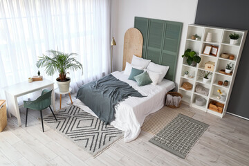 Interior of light bedroom with shelf unit, plants and table