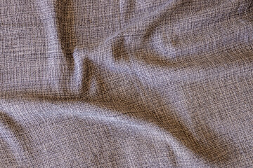 Close-up of gray, beige and white textured fabric. Intricate weave pattern and subtle folds create...