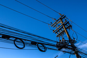 Many wires attached to the electric pole, the chaos of cables and wires on an electric pole, blue...