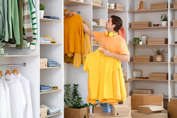 Handsome young man arranging stylish clothes in dressing room