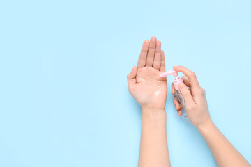 Woman applying sanitizer on her hands against blue background