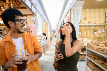 Happy couple laughing and enjoying shopping spree at street market in Bangkok