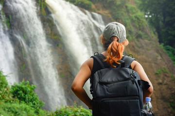 Adventurous woman gazing at waterfall while hiking. Concept of exploration and outdoor freedom.