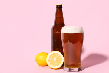 Bottle and glass of fresh beer with lemon on pink background