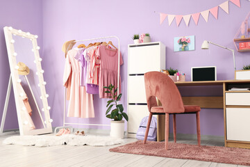 Interior of stylish teenager's room with workplace, mirror and clothes rack
