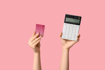Female hands with credit card and calculator on pink background