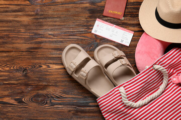 Travel pillow, passport, ticket and beach accessories on wooden background