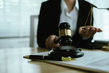 Lawyer sitting at desk in modern office reviewing and signing legal documents related to finance,...