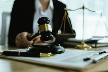Lawyer sitting at desk in modern office reviewing and signing legal documents related to finance,...