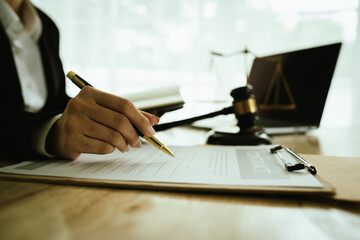 Lawyer sitting at desk in modern office reviewing and signing legal documents related to finance,...
