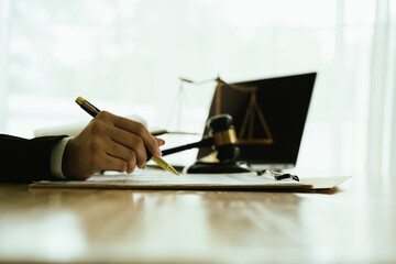 Lawyer sitting at desk in modern office reviewing and signing legal documents related to finance,...