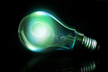 Light bulb with metallic screw base is emitting green-blue glow on reflective surface in 3D render