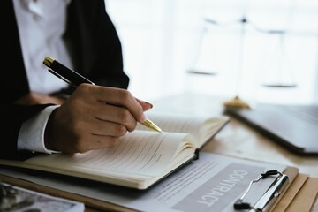 Lawyer sitting at desk in modern office reviewing and signing legal documents related to finance, equity and contractual agreements in business law.
