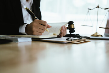 Lawyer sitting at desk in modern office reviewing and signing legal documents related to finance,...