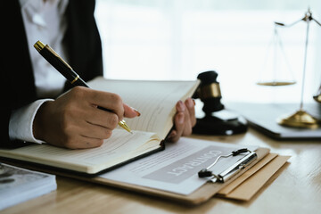 Lawyer sitting at desk in modern office reviewing and signing legal documents related to finance, equity and contractual agreements in business law.