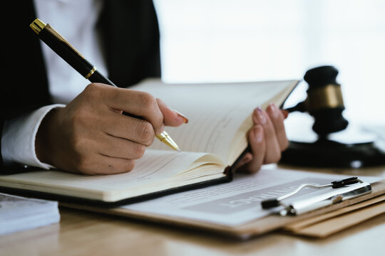 Lawyer sitting at desk in modern office reviewing and signing legal documents related to finance, equity and contractual agreements in business law.