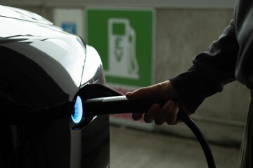 Man charging electric car at charging station