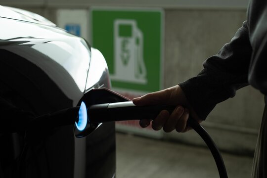 Fototapeta Man charging electric car at charging station