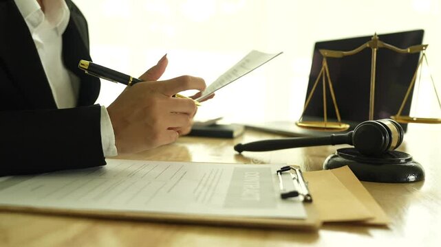 Lawyer sitting at desk in modern office reviewing and signing legal documents related to finance, equity and contractual agreements in business law.