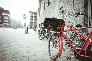 Red bicycle with front crate is leaning against stone wall on paved sidewalk in flat design