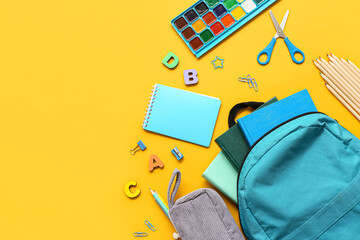 Modern school backpack with different stationery supplies on yellow background