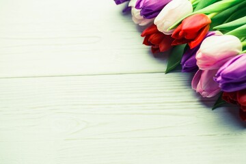 Obraz premium Multicolored tulip bouquet is resting in flat design flat-lay on painted wooden table, copy space
