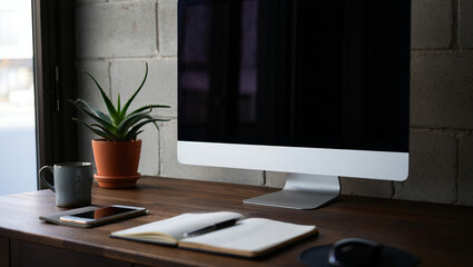 Modern minimalist workspace: desktop computer, notebook, succulent plant, and smartphone.