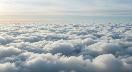 View from above the clouds during sunset, a serene and ethereal landscape filled with soft, fluffy white clouds stretching to the horizon under a warm sky.
