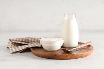 Glass bowl and bottle of tasty yogurt on white background