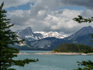 Snowy mountains and island on a lake in Peter Lougheed Provincial Park, Alberta. Dramatic clouds...