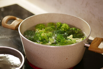 Broccoli cooking in a pot on a stovetop in the kitchen