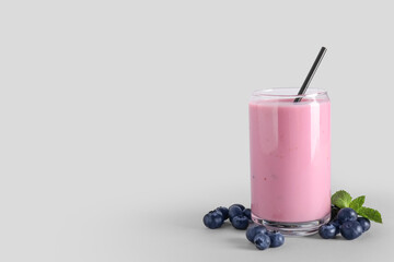 Glass of fresh blueberry smoothie with mint and berries on grey background