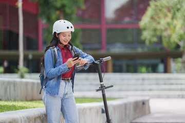 Young woman using smartphone while leaning on scooter outdoors © crizzystudio