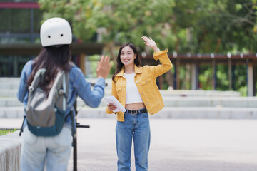 Two female students waving goodbye on university campus