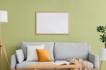 Stylish grey sofa with pillows near green wall in room