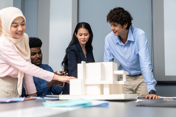 Architects engineers collaborating on building design project in modern office, diverse team of professionals female muslim architect and male engineers discussing architectural model of structure