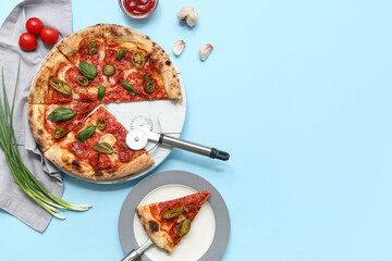 Composition with tasty pizza, ingredients and cutter on blue background