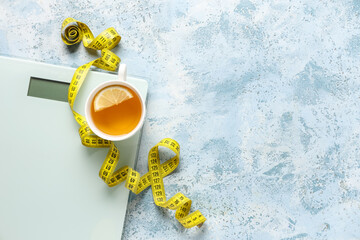 Cup of diet tea, measuring tape and scales on color background. Weight loss concept