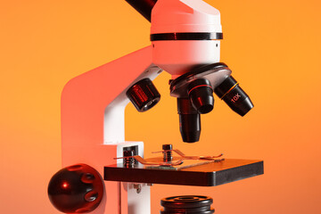 Modern microscope on orange background, closeup
