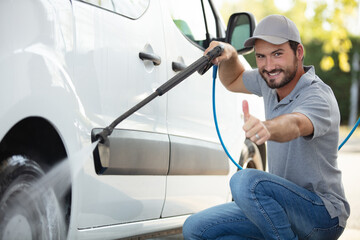 man washing his car under high pressure water outdoors