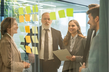 Businesspeople talking in their diverse team during a brainstorming session with sticky notes on...