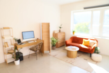 Interior of living room with sofa, coffee table and modern workplace. Blurred view